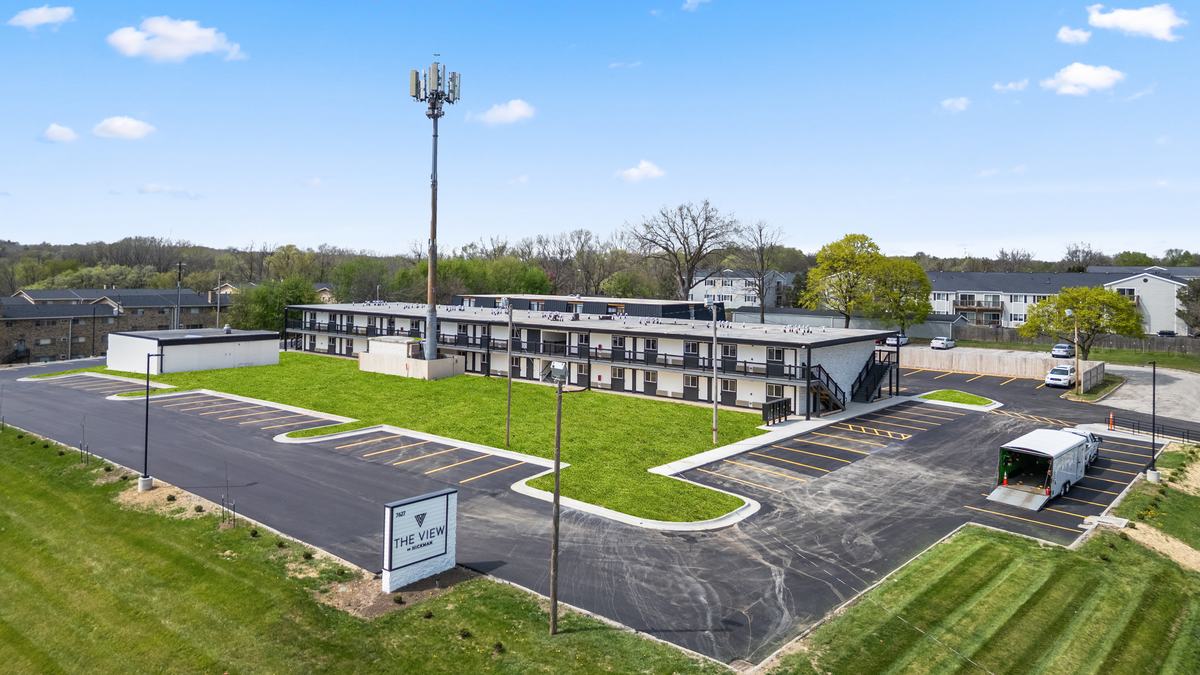 Aerial view of the property showing the long two-story building, the striped parking lot and the surrounding Urbandale neighborhood.